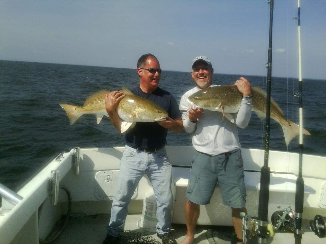 Two men smile while holding up their fish