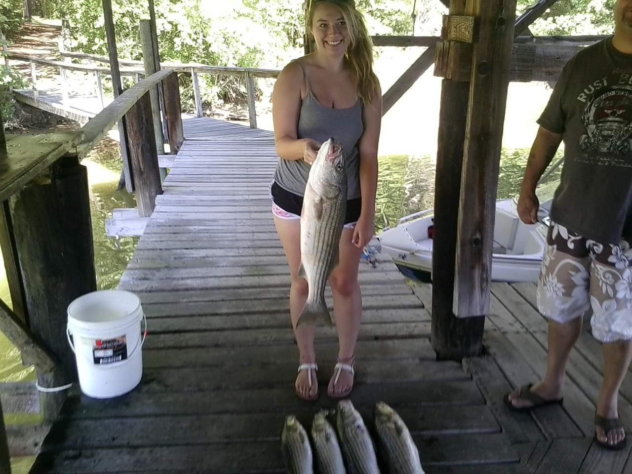 Woman smiles while holding up her caught fish on the dock