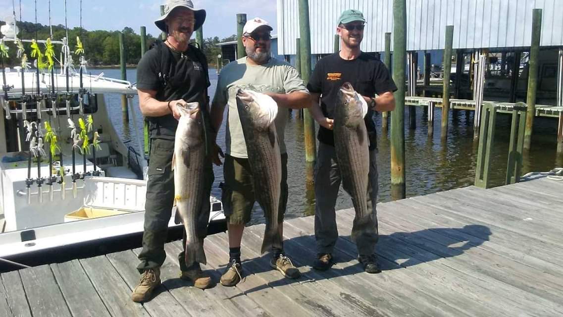 Three customers houlding up their caught fish